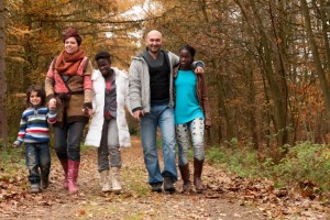 Family with 3 adopted children from diverse backgrounds, taking a walk in the park