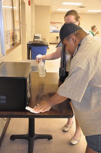 man cleaning in a lunchroom. He is receiving assistance from a supervisor.