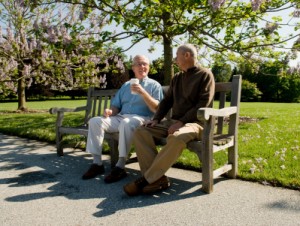 2 older men sitting and chatting on a park bench