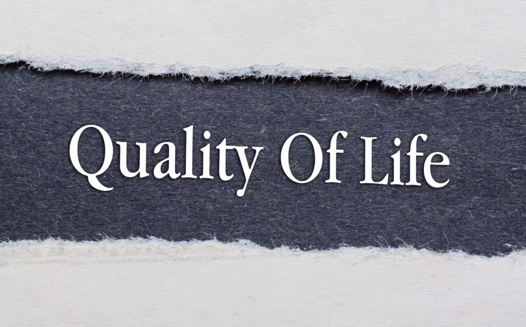 A piece of paper is ripped in the middle to show gray paper under it. On the gray paper is written quality of life in white text.