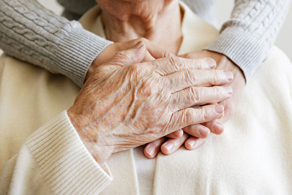 A close-up of two elderly hands gently holding each other.