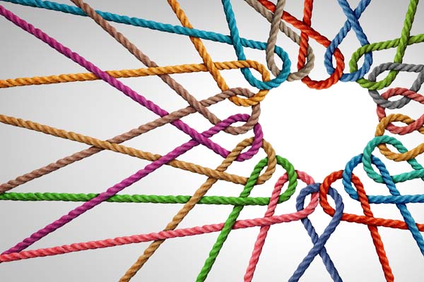 A series of colorful ropes are arranged so that they are intertwined and knotted together. At the center the shape of a heart is created using negative space where there are no ropes.