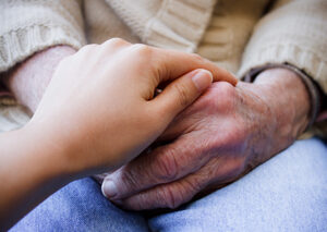 A younger person's hand holding an older person's hand