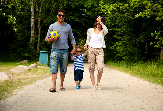 A family holding hand while walking down a dirt road