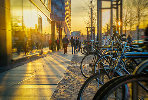 A sidewalk with people and bikes at sunset