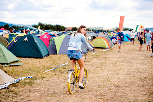 A teenage girl riding a bike through a campground