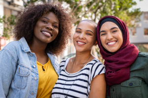 A group of three young multicultural women smiling.