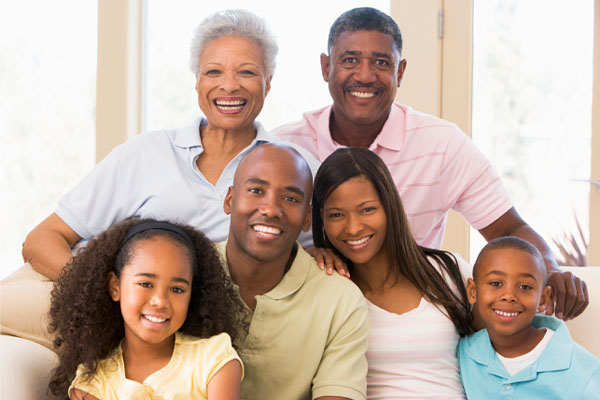 A picture of a happy family. There are six people who are all smiling and appear to be enjoying each other's company. The group includes an older woman, an older man, a woman, a young girl, a man, and a young boy.